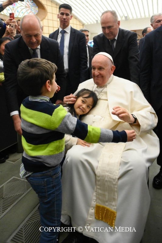 Dos niños se abrazan al Papa Francisco